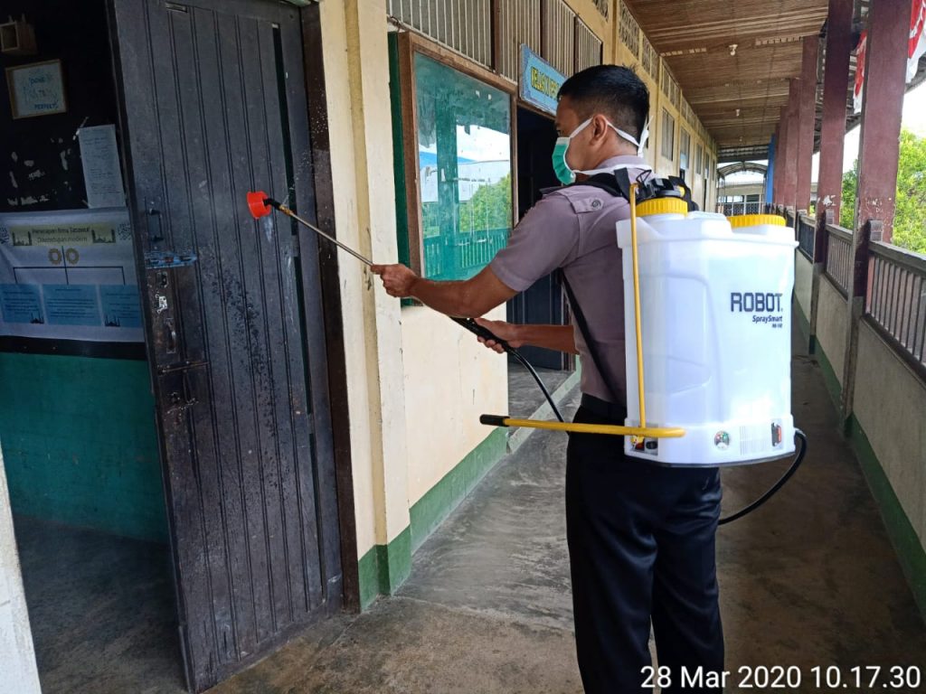 Anggota kepolisian menyemprotkan disinfektan di Ponpes Ushuluddin Singkawang 