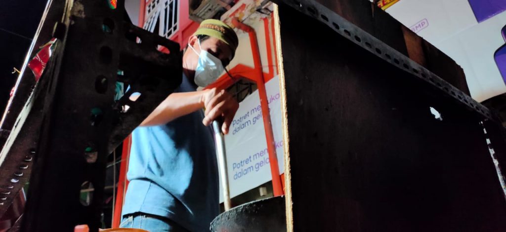 Agus, pedagang makanan di belakang pekong pasar sedang mengemas makanan pesanan konsumen